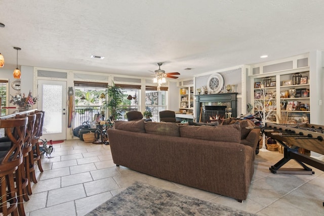 355 Cumberland Trl, Conroe, TX 77302 - living room featuring a premium fireplace, a textured ceiling, ceiling fan, and light tile patterned flooring