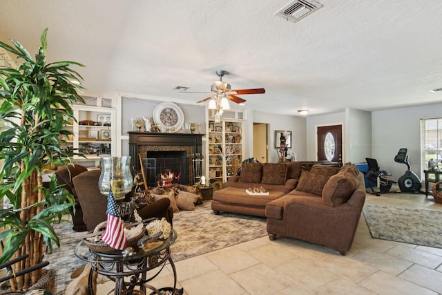 355 Cumberland Trl, Conroe, TX 77302 - tiled living area featuring a warm lit fireplace, ceiling fan, a textured ceiling, and built in shelves