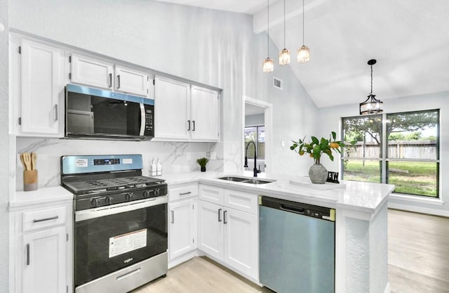 16307 N Mist Dr, Houston, TX 77073 - kitchen with stainless steel appliances, a peninsula, light wood-style floors, and white cabinets