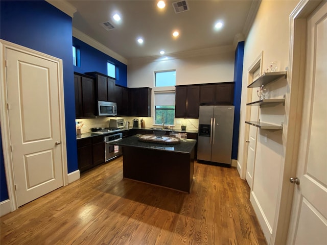 5809 Larkin St, Houston, TX 77007 - kitchen featuring appliances with stainless steel finishes, ornamental molding, dark countertops, a kitchen island, and wood finished floors
