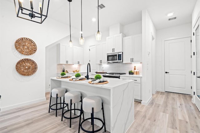 6417 Madrid St, Houston, TX 77021 - kitchen with stainless steel microwave, gas range oven, light wood-style floors, and a breakfast bar