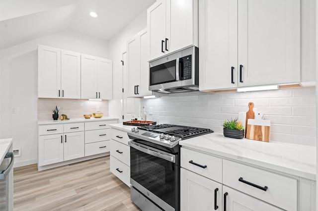 6417 Madrid St, Houston, TX 77021 - kitchen featuring stainless steel appliances, white cabinetry, light wood-style flooring, light stone countertops, and vaulted ceiling