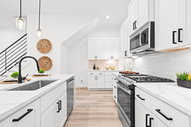 6417 Madrid St, Houston, TX 77021 - kitchen featuring stainless steel appliances, light stone countertops, white cabinetry, backsplash, and light wood-style floors