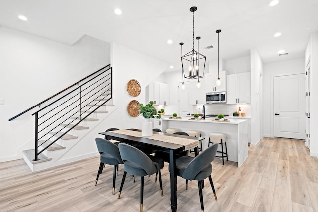 6417 Madrid St, Houston, TX 77021 - dining space featuring recessed lighting, light wood-style flooring, stairway, and a chandelier