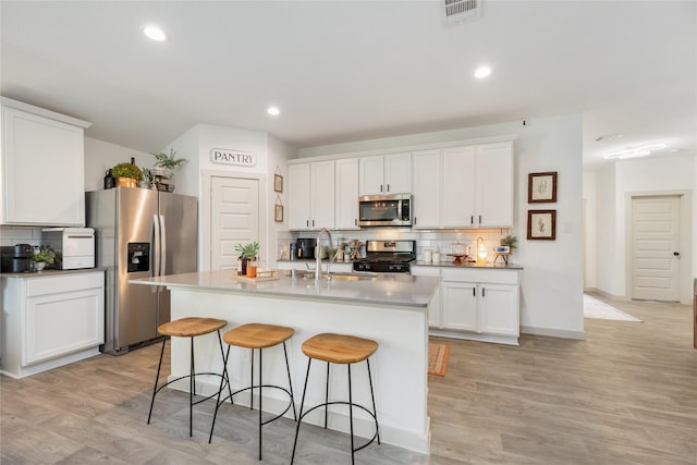 14706 Sweet Water Dr, Baytown, TX 77523 - kitchen with appliances with stainless steel finishes, backsplash, a kitchen breakfast bar, light wood-style flooring, and recessed lighting