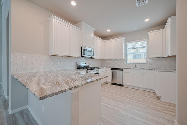 27222 Clear Breeze Dr, Katy, TX 77493 - kitchen featuring appliances with stainless steel finishes, a peninsula, light stone counters, light wood finished floors, and recessed lighting