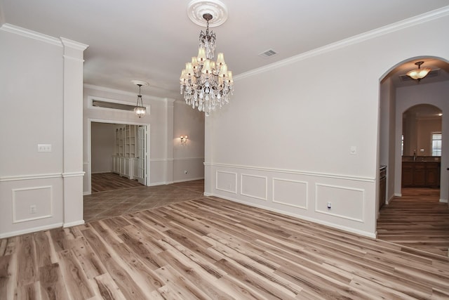 26622 Boulder Cove Ct, Katy, TX 77494 - empty room with light wood-type flooring, arched walkways, crown molding, a wainscoted wall, and a chandelier