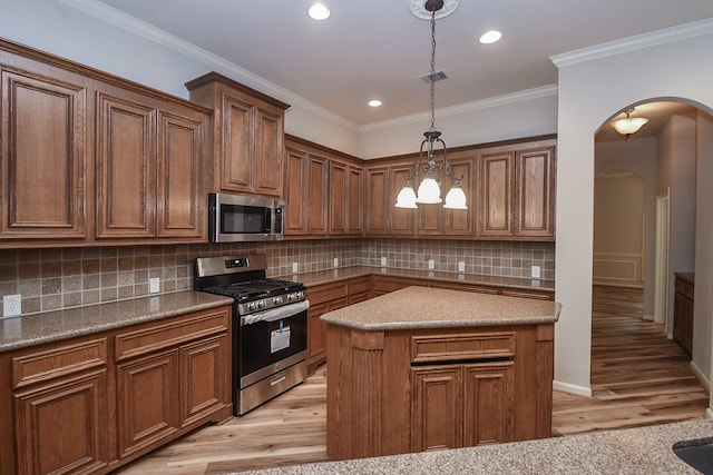 26622 Boulder Cove Ct, Katy, TX 77494 - kitchen with stainless steel appliances, arched walkways, light wood-style flooring, hanging light fixtures, and ornamental molding