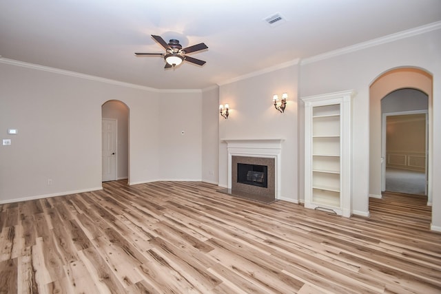 26622 Boulder Cove Ct, Katy, TX 77494 - unfurnished living room with arched walkways, a ceiling fan, light wood finished floors, crown molding, and a fireplace with flush hearth