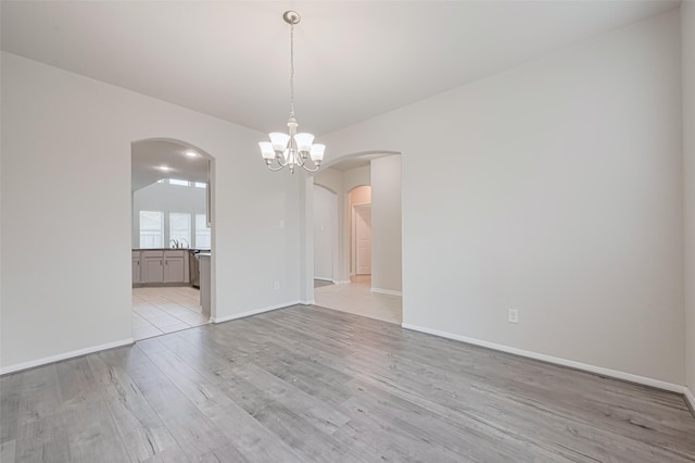23607 Acerola Tree Ct, Katy, TX 77493 - unfurnished room with arched walkways, light wood-style floors, and a chandelier