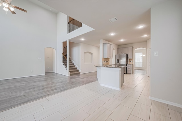 23607 Acerola Tree Ct, Katy, TX 77493 - kitchen featuring arched walkways, a ceiling fan, stainless steel refrigerator with ice dispenser, open floor plan, and dark stone countertops