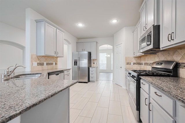 23607 Acerola Tree Ct, Katy, TX 77493 - kitchen with stainless steel appliances, arched walkways, light stone counters, decorative backsplash, and recessed lighting