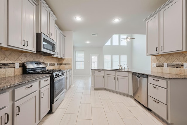 23607 Acerola Tree Ct, Katy, TX 77493 - kitchen featuring appliances with stainless steel finishes, a peninsula, a ceiling fan, stone countertops, and tasteful backsplash