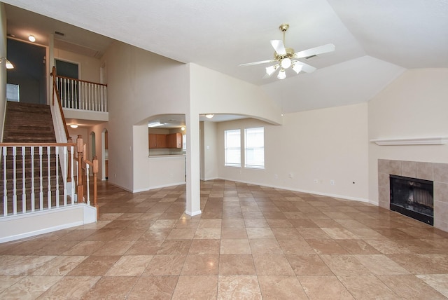 19727 Hon Ct, Katy, TX 77449 - unfurnished living room with ceiling fan, vaulted ceiling, stairway, a tile fireplace, and arched walkways