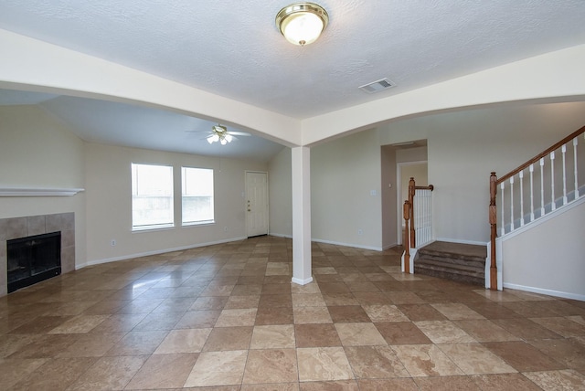 19727 Hon Ct, Katy, TX 77449 - unfurnished living room with a ceiling fan, a tile fireplace, stairway, light stone finish flooring, and a textured ceiling