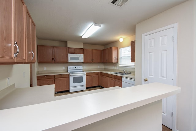 19727 Hon Ct, Katy, TX 77449 - kitchen featuring white appliances, light countertops, brown cabinets, and a peninsula
