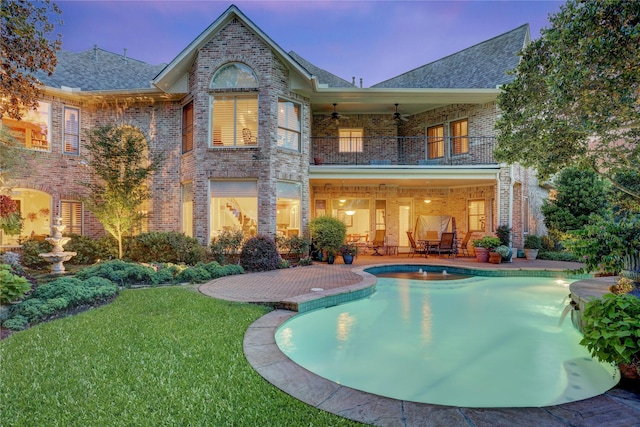 3207 Riviera Dr, Sugar Land, TX 77479 - back of house at dusk featuring a balcony, brick siding, ceiling fan, and a patio