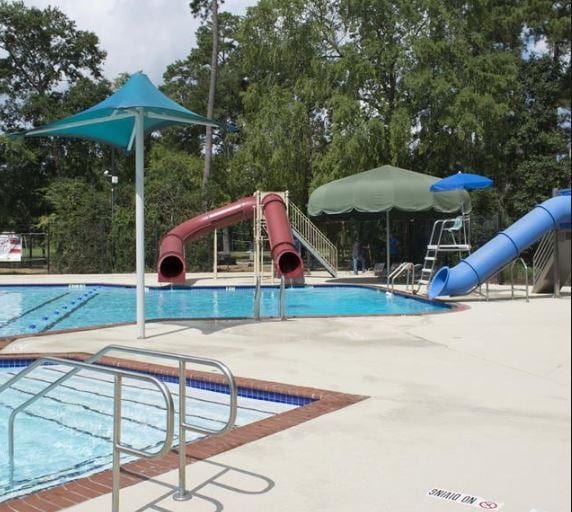 291 E Rainbow Ridge Cir, The Woodlands, TX 77381 - community pool featuring a water slide, a patio, and view of scattered trees