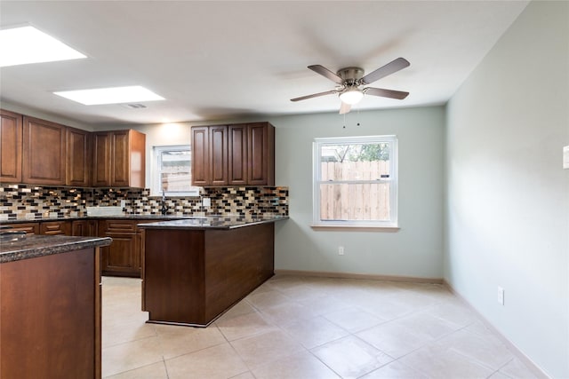 5402 Sheraton Oaks Dr, Houston, TX 77091 - kitchen with tasteful backsplash, a peninsula, a ceiling fan, light tile patterned floors, and dark stone countertops