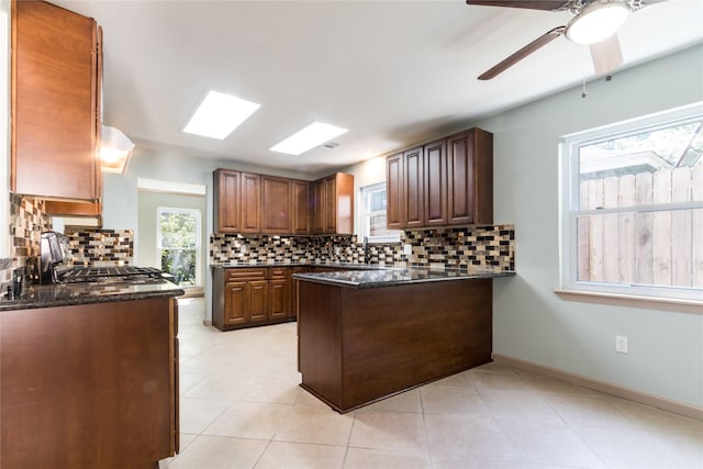 5402 Sheraton Oaks Dr, Houston, TX 77091 - kitchen featuring ceiling fan, a peninsula, backsplash, and dark stone countertops