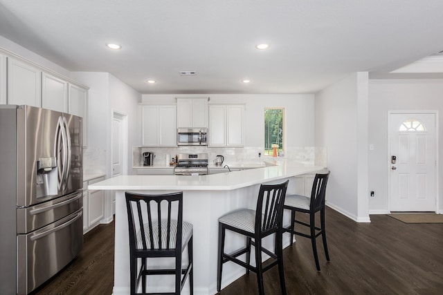 2018 Rd 660, Dayton, TX 77535 - kitchen with stainless steel appliances, dark wood-style floors, a breakfast bar, tasteful backsplash, and recessed lighting