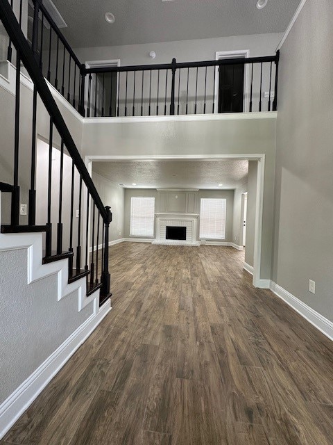 2102 Autumn Cove Dr, League City, TX 77573 - unfurnished living room featuring a towering ceiling, wood finished floors, stairway, and a fireplace