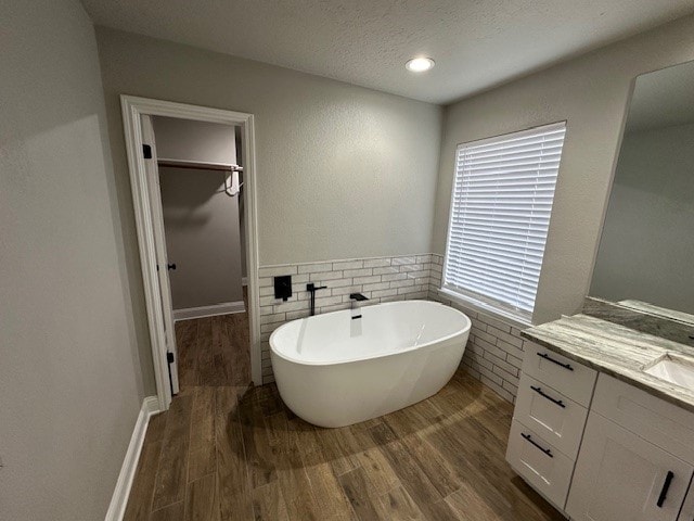 2102 Autumn Cove Dr, League City, TX 77573 - full bathroom with a walk in closet, vanity, wood finished floors, a freestanding bath, and tile walls