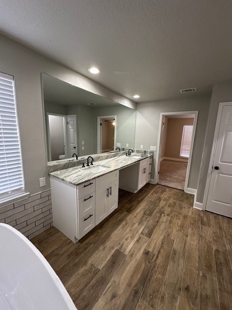 2102 Autumn Cove Dr, League City, TX 77573 - full bath featuring wood finished floors, double vanity, a freestanding tub, recessed lighting, and a textured ceiling