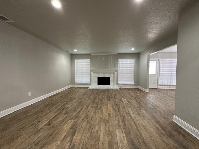 2102 Autumn Cove Dr, League City, TX 77573 - unfurnished living room featuring dark wood-type flooring, a brick fireplace, recessed lighting, and a textured ceiling