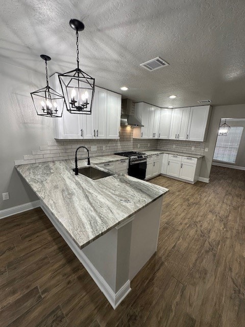 2102 Autumn Cove Dr, League City, TX 77573 - kitchen with stainless steel range with gas cooktop, light stone countertops, white cabinets, a chandelier, and a peninsula