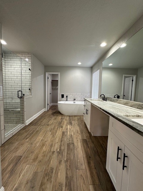 2102 Autumn Cove Dr, League City, TX 77573 - bathroom with double vanity, a shower stall, wood finished floors, a soaking tub, and recessed lighting