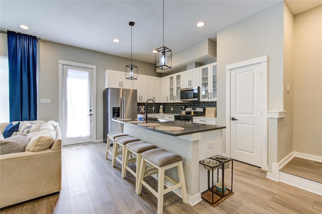 320 Parker Willow Ln, Houston, TX 77076 - kitchen with appliances with stainless steel finishes, a breakfast bar area, backsplash, glass insert cabinets, and light wood finished floors