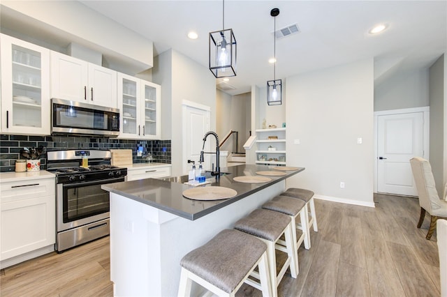 320 Parker Willow Ln, Houston, TX 77076 - kitchen featuring appliances with stainless steel finishes, a breakfast bar area, light wood finished floors, decorative backsplash, and white cabinets