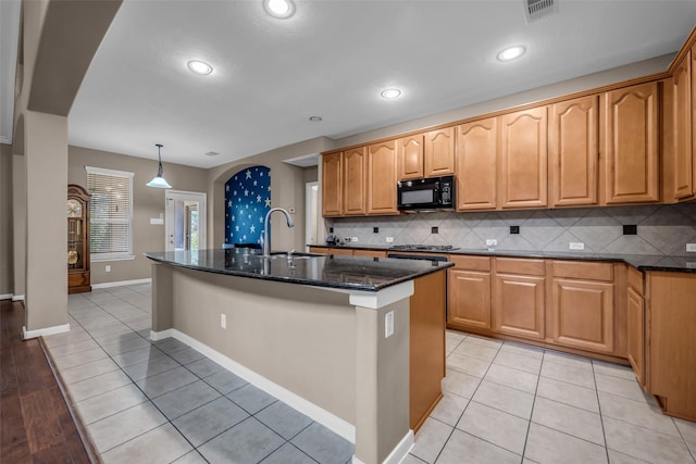 5531 Cherish Trl, Katy, TX 77494 - kitchen with black microwave, a kitchen island with sink, dark stone counters, tasteful backsplash, and arched walkways