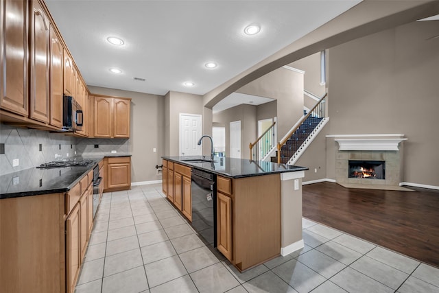 5531 Cherish Trl, Katy, TX 77494 - kitchen featuring black appliances, light tile patterned floors, backsplash, open floor plan, and dark stone countertops