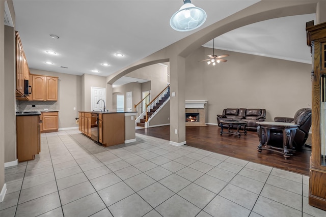 5531 Cherish Trl, Katy, TX 77494 - kitchen with open floor plan, light tile patterned flooring, a ceiling fan, a tiled fireplace, and arched walkways