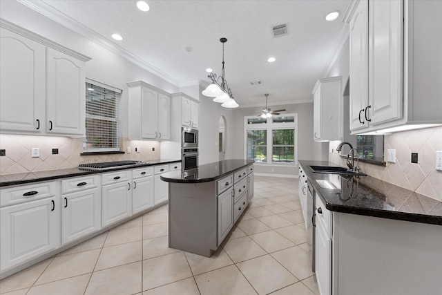 27210 Hitching Post Ct, Magnolia, TX 77355 - kitchen with stainless steel appliances, crown molding, ceiling fan, white cabinets, and a center island
