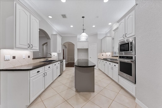 27210 Hitching Post Ct, Magnolia, TX 77355 - kitchen featuring stainless steel appliances, arched walkways, dark countertops, tasteful backsplash, and crown molding