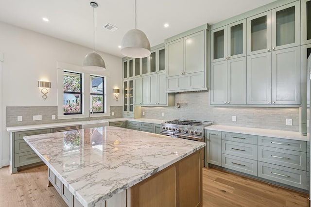 1023 Grovewood Ln, Houston, TX 77008 - kitchen with light stone countertops, decorative backsplash, light wood-style flooring, a kitchen island, and recessed lighting