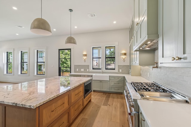 1023 Grovewood Ln, Houston, TX 77008 - kitchen featuring stove, stainless steel microwave, light wood-style floors, tasteful backsplash, and a kitchen island