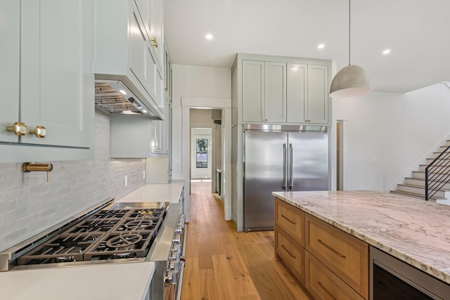 1023 Grovewood Ln, Houston, TX 77008 - kitchen featuring appliances with stainless steel finishes, decorative backsplash, light wood-style flooring, light stone counters, and pendant lighting