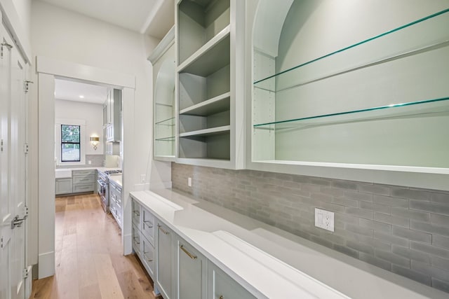 1023 Grovewood Ln, Houston, TX 77008 - bar featuring tasteful backsplash, light wood-style floors, and high end stainless steel range