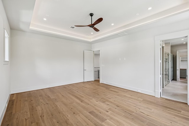 1023 Grovewood Ln, Houston, TX 77008 - spare room with ceiling fan, a tray ceiling, light wood-style floors, and recessed lighting