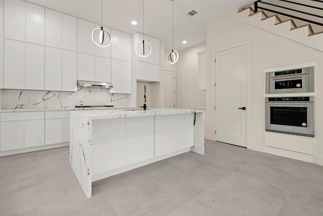5117 Schuler St Unit B, Houston, TX 77007 - kitchen featuring under cabinet range hood, white cabinets, a kitchen island with sink, tasteful backsplash, and modern cabinets