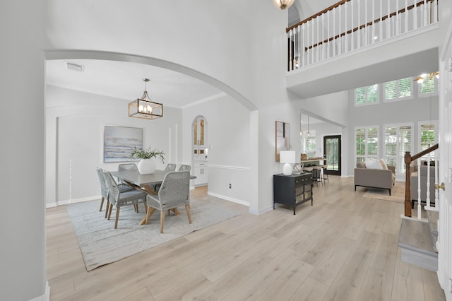 1622 Maryvale Dr, Katy, TX 77494 - dining room featuring arched walkways, a chandelier, wood finished floors, and a towering ceiling