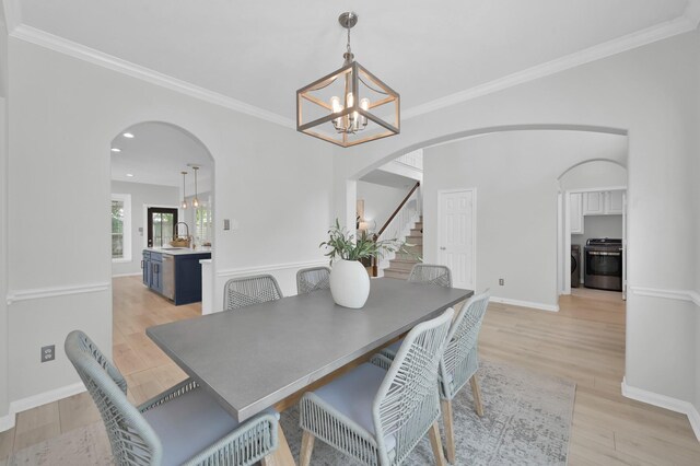 1622 Maryvale Dr, Katy, TX 77494 - dining area featuring arched walkways, a chandelier, crown molding, light wood-style floors, and stairs