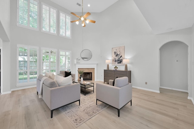 1622 Maryvale Dr, Katy, TX 77494 - living area with arched walkways, high vaulted ceiling, ceiling fan, a high end fireplace, and light wood finished floors