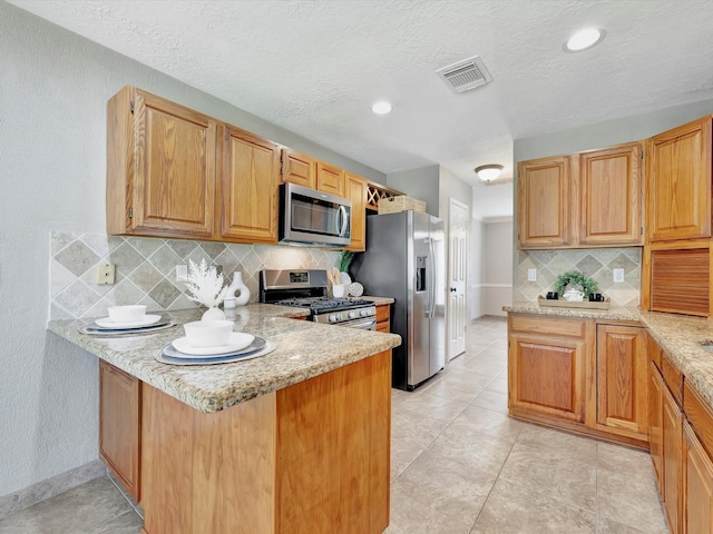 1227 Redwood Bough Ln, Houston, TX 77062 - kitchen with stainless steel appliances, a peninsula, decorative backsplash, light stone counters, and a textured ceiling