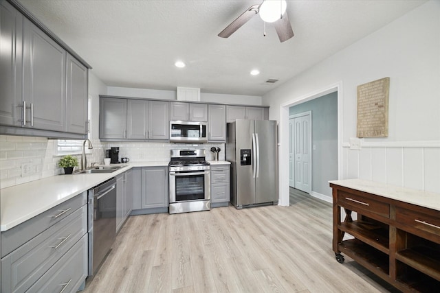 1115 Alber St, Houston, TX 77009 - kitchen with gray cabinets, appliances with stainless steel finishes, decorative backsplash, light wood-style floors, and a ceiling fan