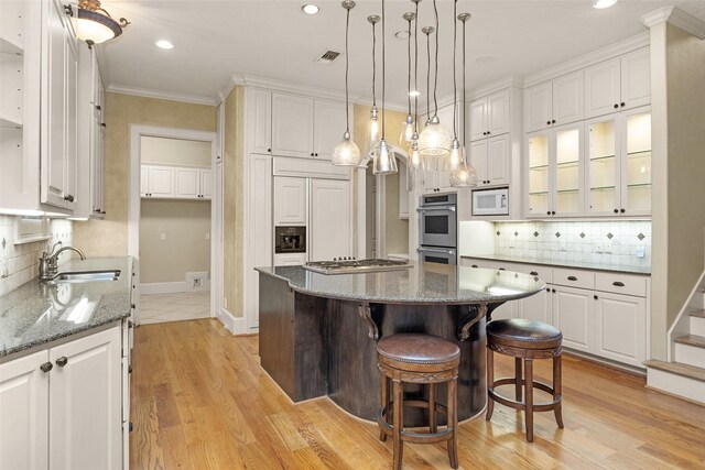 6616 Queensclub Dr, Houston, TX 77069 - kitchen with built in appliances, white cabinets, a center island, decorative backsplash, and crown molding